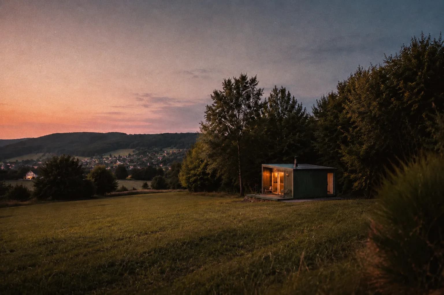 Tiny House bei Abenddämmerung auf einer Wiese in der Natur